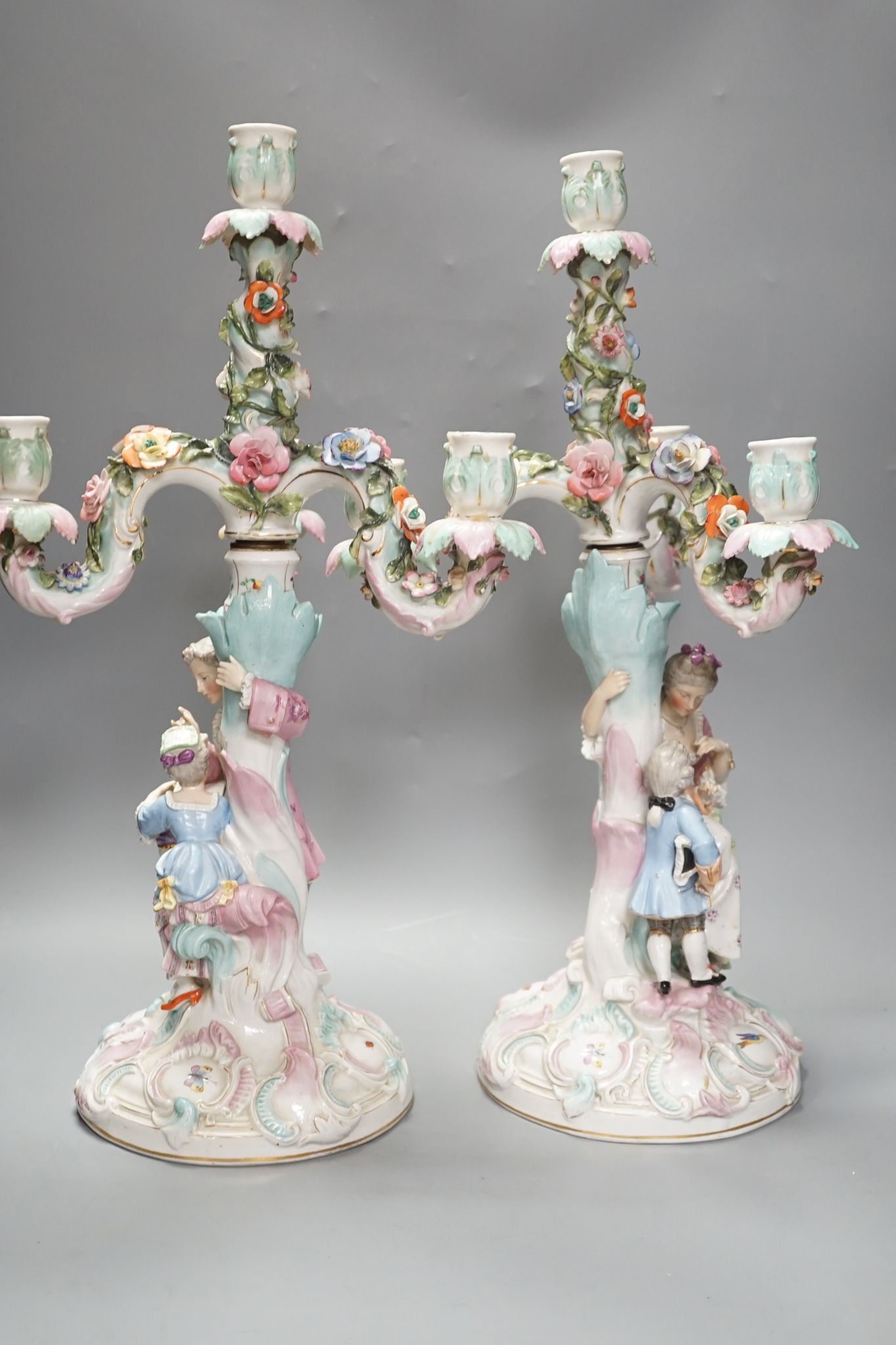 A pair of late 19th century German floral encrusted, figurative porcelain candelabra, 52 cms high.